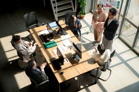 Multicultural business team standing around a conference table during meetings, discussing charts