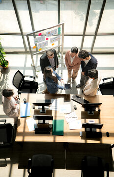 Multicultural business team standing around a desk and reviewing information on a tablet