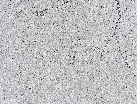 Abstract Grey Porous AAC Brick Surface Texture. High-detail top-view of a grey textured surface with tiny holes and pores, resembling concrete, stone, or solidified foam.
