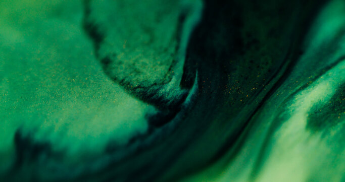 Defocused paint stream. Acrylic spill. Black fluid flow on green shimmering texture. Swirl color blend abstract drip mess background.
