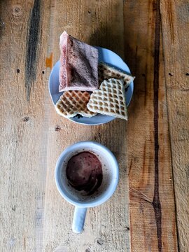 Cup of coffee  drink served with traditional Indonesian snacks from maluku made by cassava and sago, (embal and sagu lempeng )on a wooden table