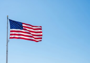 National flag of the United States of America waving in the wind against a clear blue sky. Symbol of freedom, democracy and independence. Background with copy space for text.