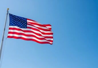 Obraz premium National flag of the United States of America waving in the wind against a clear blue sky. Symbol of freedom, democracy and independence. Background with copy space for text.
