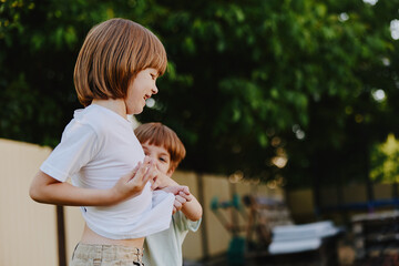 Obraz premium Two playful boys enjoying a sunny day outdoors, laughing together and engaging in friendly playfulness, surrounded by greenery and warm sunlight.
