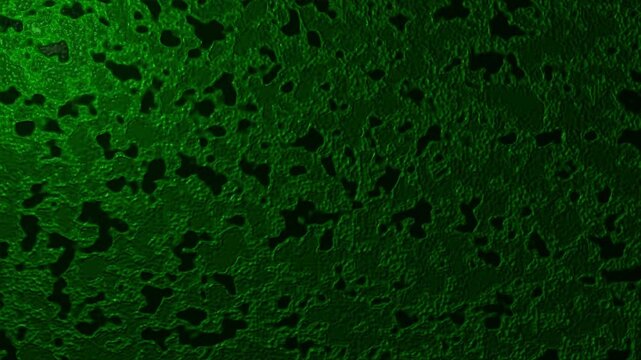 An abstract green textured background with varying shades and black speckles, creating a dynamic and visually interesting surface.