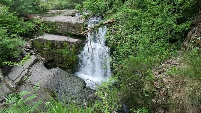 Aerial drone view of Akchour waterfall flowing through rocky forest landscape in Chefchaouen region Morocco showing fresh water movement surrounded by green natural scenery