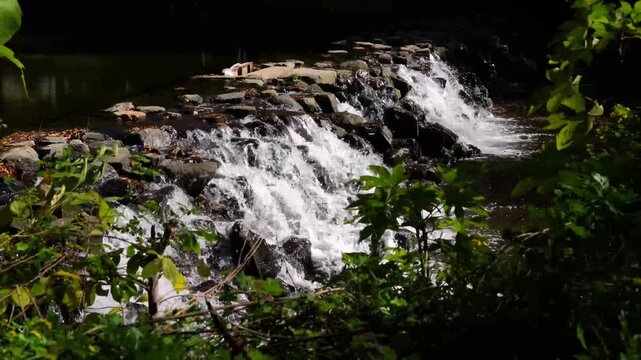 Forest stream flowing over rocks forming small waterfall in Akchour Chefchaouen Morocco surrounded by dense greenery and natural woodland landscape