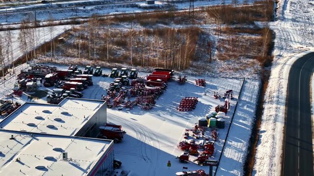 Drone shot of a snow-covered farm equipment depot with multiple tractors in Latvia