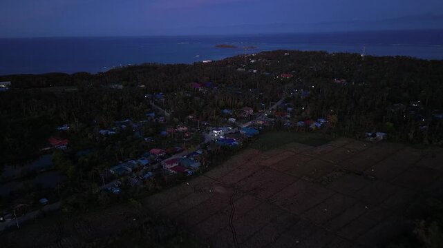 Smooth sideways drone pan across rice fields and rural road in Tondol, enhanced by soft sunset light.