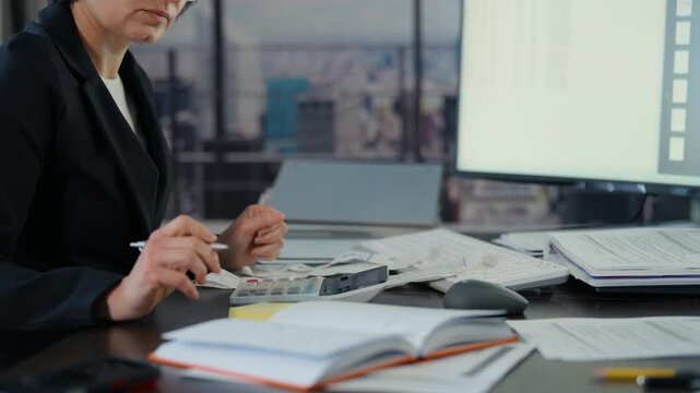 Business woman accountant making notes and calculations of financial data sheet with calculator and computer., Business and financial concept.
