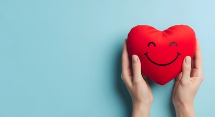 Fototapeta premium A person holding a smiling red heart shaped pillow