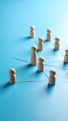 Wooden figurines connected by lines on a blue background, representing a network