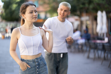 Obraz premium Young girl squabble with partner about jealousy. Husband and wife quarrel during walk, make accusations, bicker. Person tries to engage offended interlocutor in conversation..