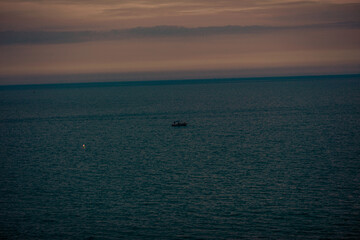 Obraz premium The background of the sea by the evening sea, with natural beauty (sea water, rocks, sky) and fishermen are fishing by the river bank, is a pleasure during travel.