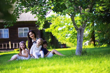 Naklejka premium Young large family on a summer morning walk. Beautiful mother with children is playing in the park.