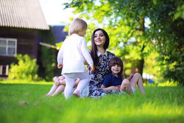 Fototapeta premium Young large family on a summer morning walk. Beautiful mother with children is playing in the park.