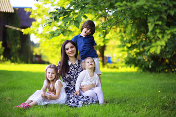 Fototapeta premium Young large family on a summer morning walk. Beautiful mother with children is playing in the park.