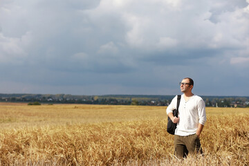 Tourist in a field of cereal plants. A man in a wheat field. Grain harvest.