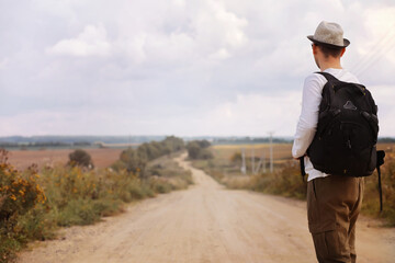 A man walks along a country road. Hitchhiker around the country. A man stops a passing car on the road.