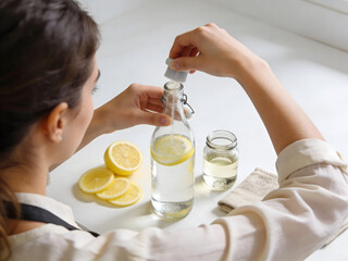 Woman preparing a homemade cleaning solution with lemon and water in a bottle graphic