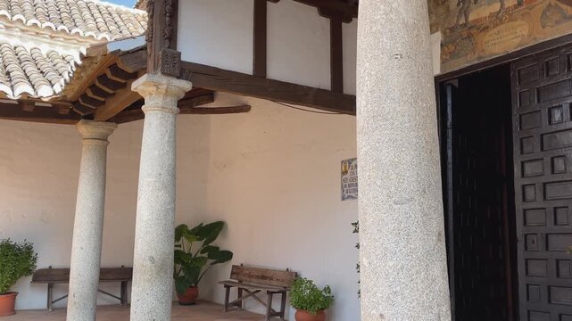 footage of a chapel entrance portico supported by granite columns with capitals.Wooden structures and ceiling show fine craftsmanship,with Arabic roof tiles and a large wooden door topped by ancient