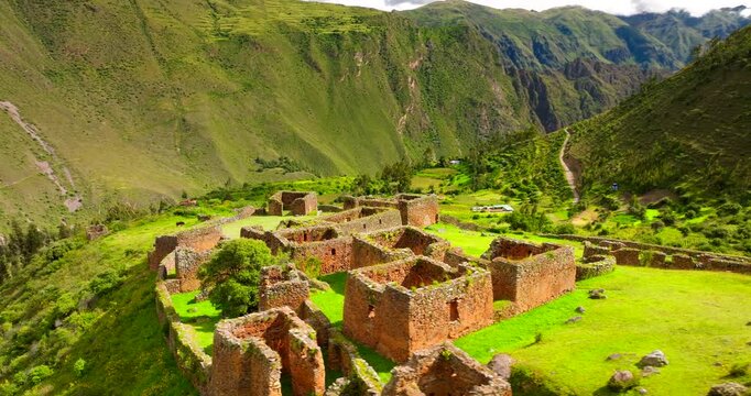Purmamarka archaeological site, showcasing ancient Inca ruins and terraces on a vibrant green mountainside in Peru. Aerial drone orbiting