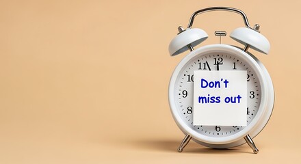 White alarm clock with sticky note saying Dont miss out. Time management concept for important events reminder.