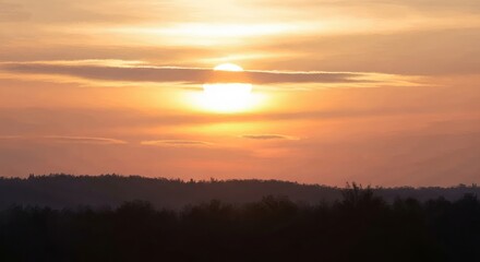 Obraz premium Sunset over a serene landscape with hills and clouds
