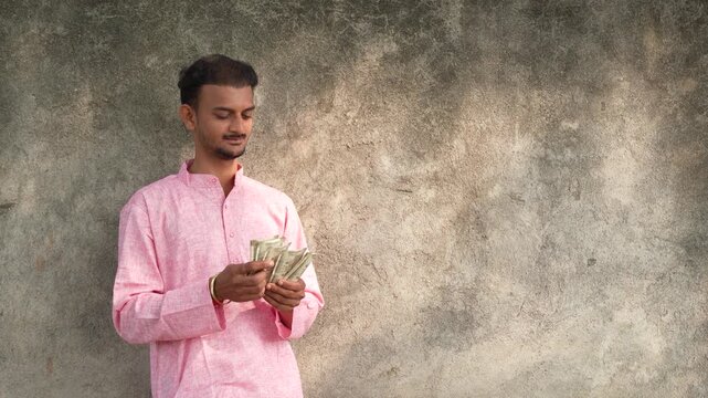 Young Indian farmer counting money at agriculture field