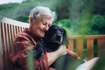 Older woman with dog sitting on terrace. © Halfpoint