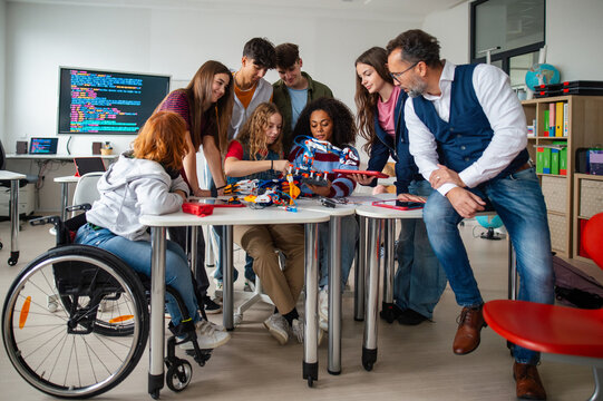 Diverse high school team celebrating teamwork during robotics project.