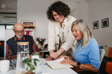 Obraz premium Female volunteer spending time with seniors in community center.