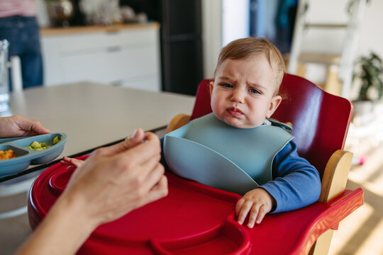Toddler crying while father feeding him.