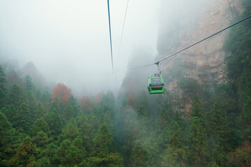 Cable car gondola floating above misty forest and towering sandstone cliffs.in Zhangjiajie National Forest Park, Hunan, China. Sustainable tourism infrastructure. Travel and tourism landmark in Asia © samael334