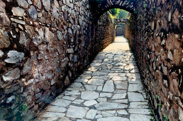 Fototapeta premium Narrow stone passage with arched openings and rough masonry walls inside a historic fortress.