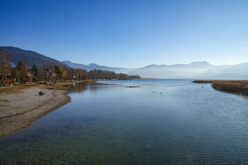 Fototapeta premium Look over the picturesque Tegernsee near Gmund in Bavaria. The alpine lake is nestled in an impressive mountain landscape.