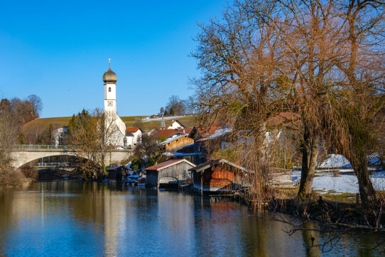 Idyllic view of Gmund in Bavaria at the outlet of the Mangfall River from Lake Tegernsee. The church of St. &Auml;gidius, the railway bridge, and the surrounding buildings are reflected in the water