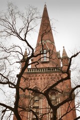 Historic church tower with red brick and cross on top.
