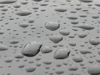 Water droplets on smooth gray surface, abstract wet texture background.