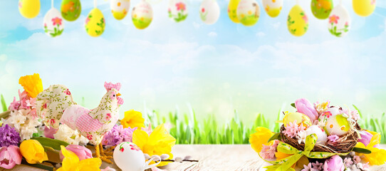 Cheerful Easter setting with decorated eggs, spring flowers, and green grass under a blue sky, ideal for festive banners, holiday promotions, and seasonal backgrounds.