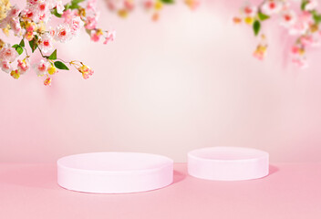 Spring concept with cylinder podiums and blooming cherry blossom branches on a pastel background for promotion product presentation