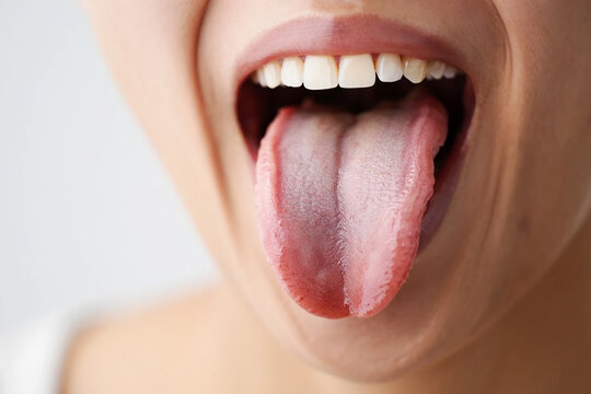 Close up of open mouth with pink tongue sticking out and white teeth image
