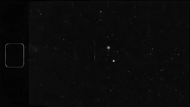 Black scratched film with white specks and a small rectangle on the left side