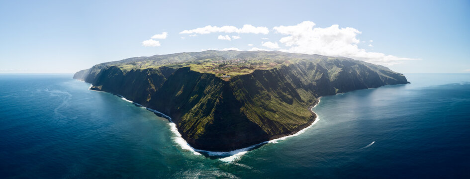 Super drone panorama of Ponta do Pargo cape and lighthouse in Madeira, Portugal. Expansive aerial view shows entire rocky headland with sheer cliffs farmland plateau and Atlantic wrapping island edge