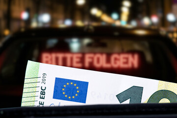 Ein Polizeiauto, Anhaltezeichen Bitte Folgen und Euro Banknote als Symbol f&uuml;r ein Bu&szlig;geld wegen einem Versto&szlig; im Stra&szlig;enverkehr