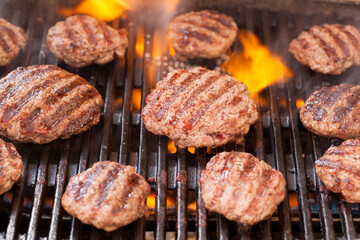 Burger patties grilling with fire and smoke