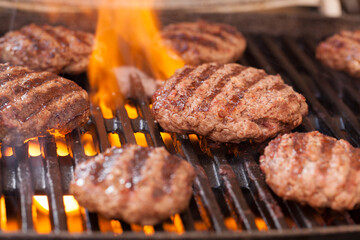 Burger patties grilling with fire and smoke