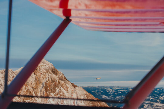Jagged mountain peaks appear through the structure of a small plane.