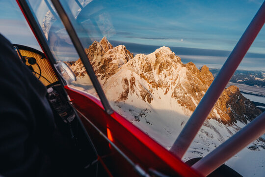 A jagged mountain peak appears through the cockpit of a small plane.
