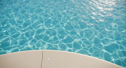 Close up view of shimmering turquoise swimming pool water surface with sun reflections and a curved concrete edge
